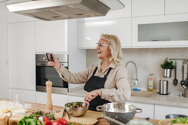 istock Senior woman making a video call while cooking a salad in her kitchen 2235050777