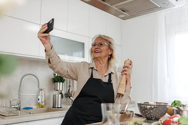 istock Senior woman taking a selfie while cooking in a modern kitchen 2235050803