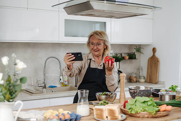 istock Senior woman showing bell pepper while making video call in kitchen 2235050834