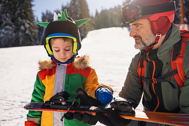 istock Father helping son prepare ski equipment on a snowy mountain slope 2235052472