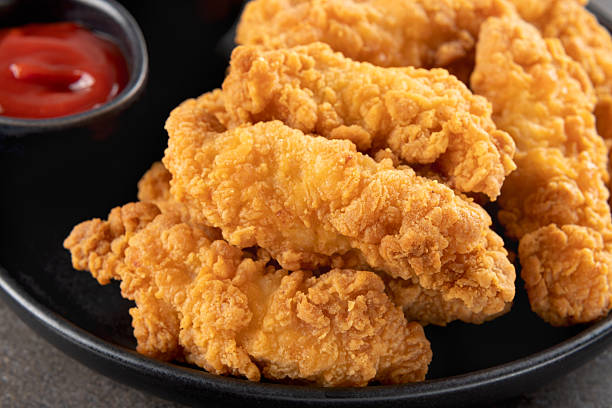 istock Crispy chicken breast strips with ketchup on a dark background. Close-up. Fast food. 2235059176
