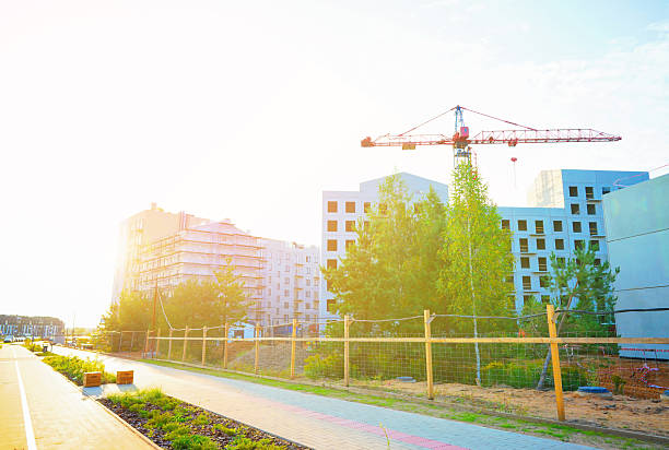 Tower Crane on building construction on bright sunset blue sky. Multi Storey Residential Buildings construction. Construction crane on Formworks on Construction site. Residential building renovation.