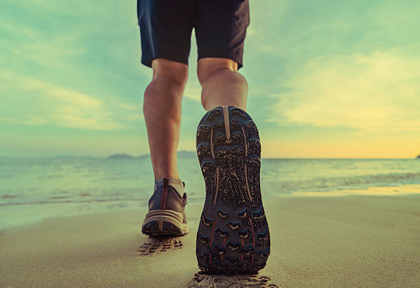 istock mans foot step on the beach, closeup 2235060819