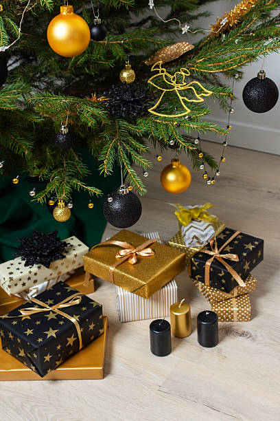 istock A festive scene featuring gold and black gift boxes, surrounded by shimmering candlelight and stylish decorations under a beautifully decorated Christmas tree, exuding elegance and charm 2235060863