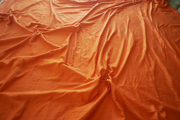 Detailed view of an orange cloth covering a flat surface indoors.