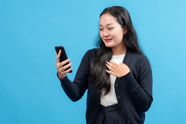 istock Happy young woman using smartphone, smiling with joy, symbolizing connectivity, modern communication, and technology, against a vibrant blue background 2235064295