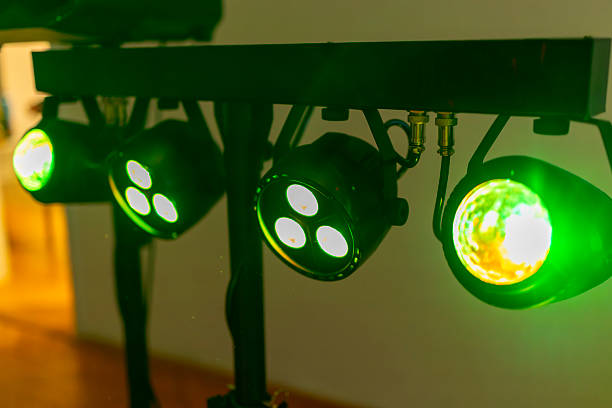Green spotlights mounted on a metal bar, illuminating a space with vibrant green light, creating an exciting atmosphere