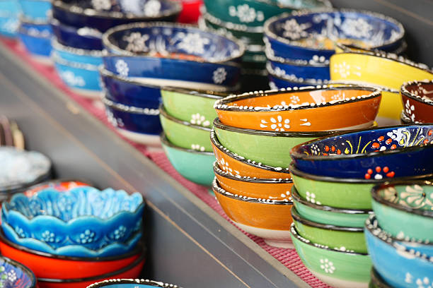 A variety of brightly colored ceramic bowls are arranged neatly for sale.