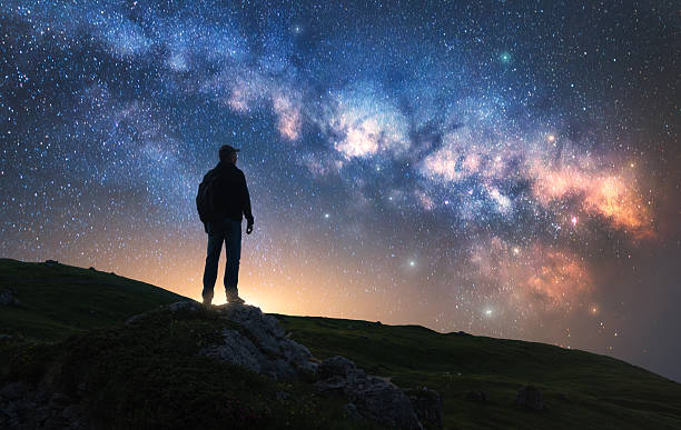 istock Glowing Milky Way and man on mountain peak at starry night 2235067507