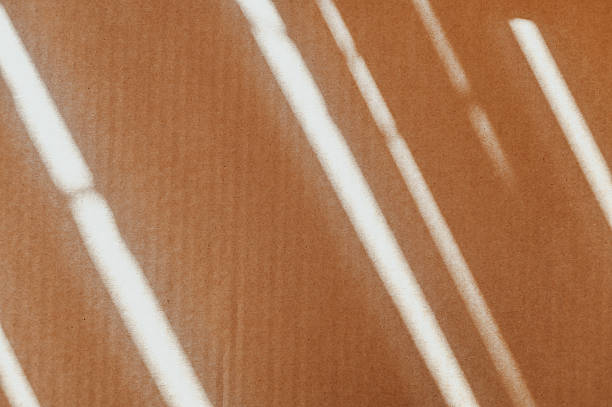 Diagonal lines of sunlight falling across a brown paper background creating an abstract pattern