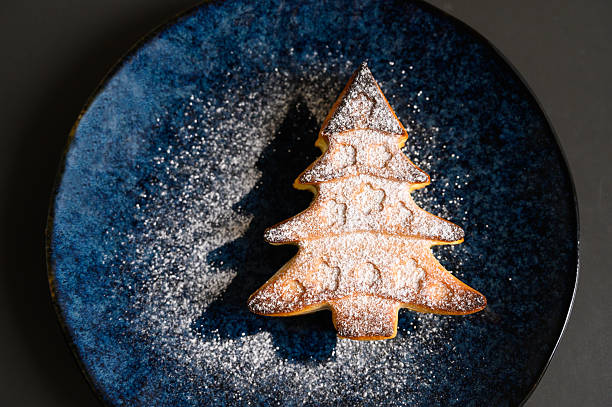 istock Christmas tree shaped cookie with sugar powder on dark plate. 2235069922