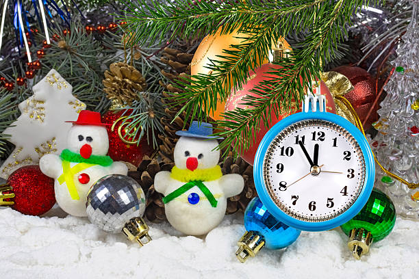Cheerful snowmen dressed in colorful scarves sit among festive ornaments and pine cones, while a bright clock ticks down to a joyful celebration, capturing the spirit of winter fun.