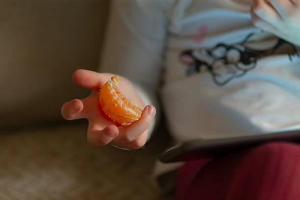 istock A young child joyfully enjoys a segment of orange while playing at home 2235070107