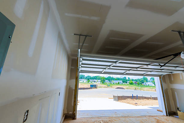 istock Newly constructed garage interior with drywall open door revealing construction site outside 2235075196