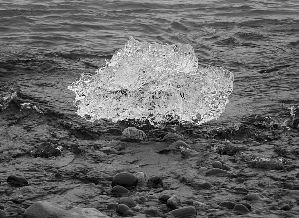 block of ice on black and volcanic sand