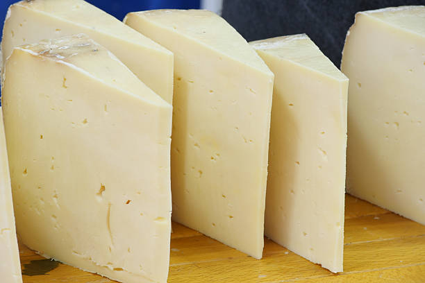 istock Delicious cheese slices arranged on a wooden cutting board 2235082776