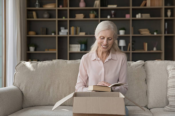 istock Happy older woman bookstore client open parcel with ordered books 2235092139