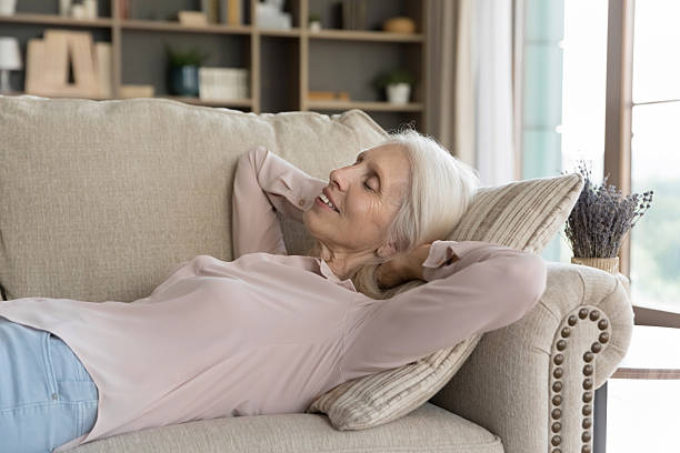 istock Smiling senior lady lying on sofa on back dreaming resting 2235092433