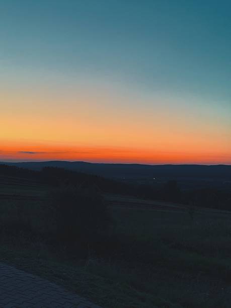 Vibrant sunset over a tranquil valley with a river winding through the landscape at dusk
