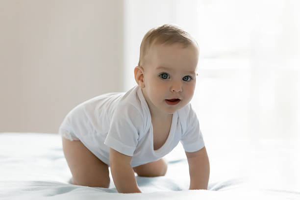 istock Portrait curious excited small infant baby crawling on large bed 2235096213