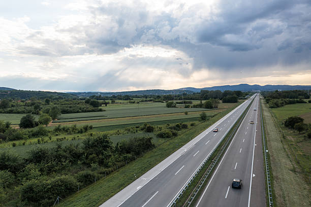 istock Scenic Countryside Highway with Lush Fields Beneath Expansive Cloudy Skies 2235098070