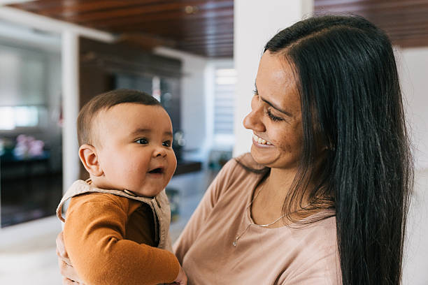 istock Mother smiling at baby while holding child 2235101707