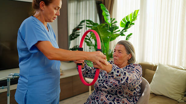 istock Female nurse having elderly woman perform rehabilitation exercises using training equipment 2235101736