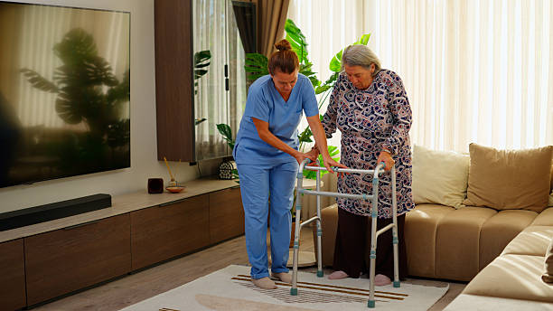 istock Female nurse helping elderly woman practice walking with walking frame 2235102270