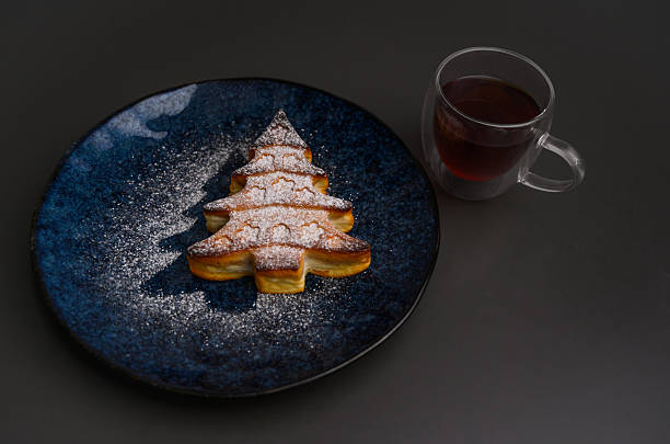 istock Christmas tree cake with powdered sugar and tea cup. 2235103791