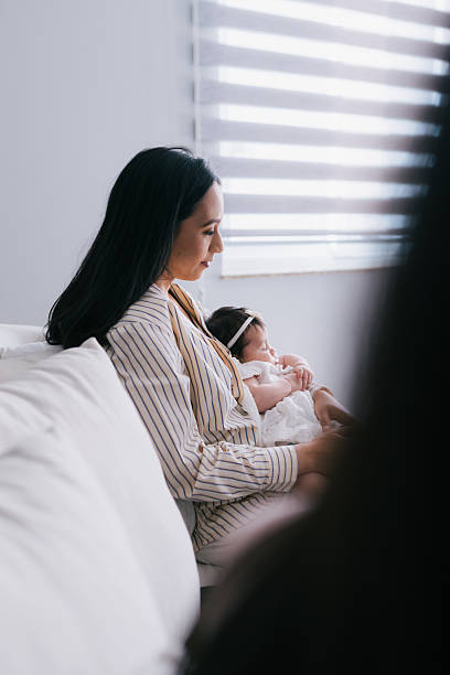 istock mom nursing infant while sitting on couch 2235104460