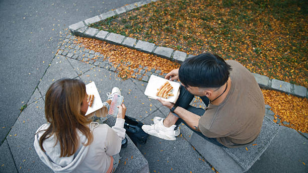 istock Caucasian Pair Sharing Pizza and Engaging with Smartphone Outdoors 2235104802