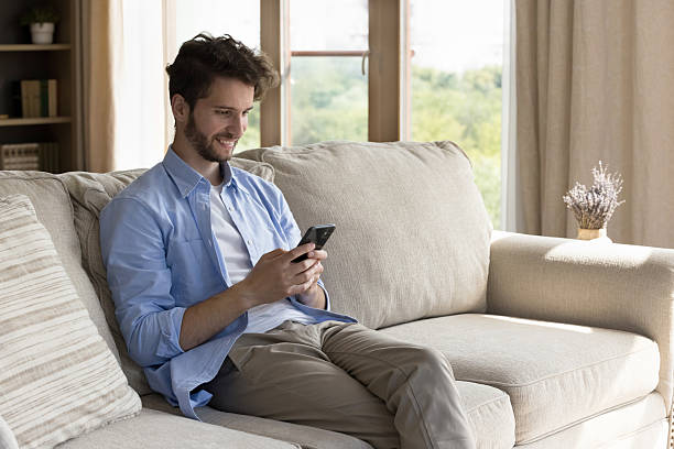 istock Engaged young hipster male lounge on couch using cellphone 2235106055