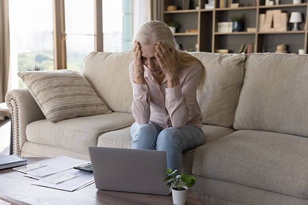 istock Frustrated older woman sitting on couch overwhelmed by financial problems 2235106980