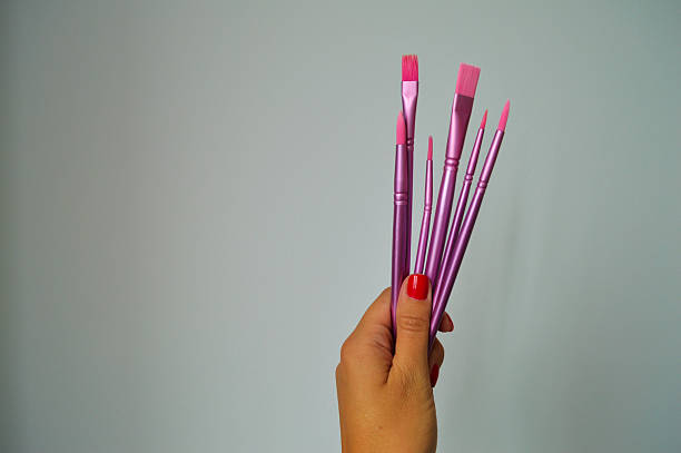 istock Five Pink Paintbrushes Held in Hand with Red Nail Polish 2235107150