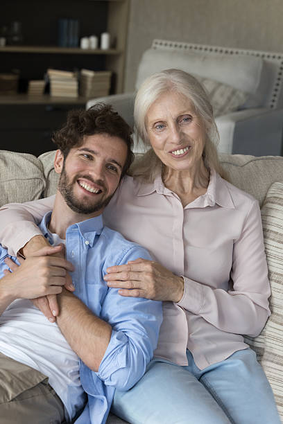 istock Smiling grown son relax on sofa cuddling affectionate senior mother 2235107558