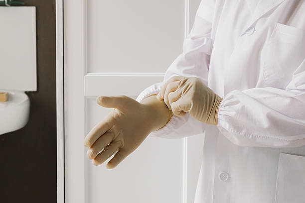 istock Mature nurse putting on sterile gloves. 2235111231