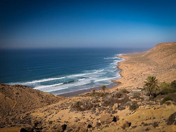 istock Secluded sandy beach with rolling waves breaking along the rugged coastline 2235116816