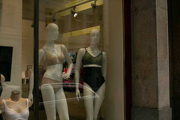 In the retail store window, there are three mannequins elegantly displayed showcasing various clothing items for customers to see