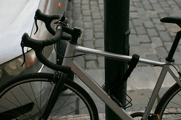 istock A bicycle is securely chained to a pole that is located next to a car 2235119932
