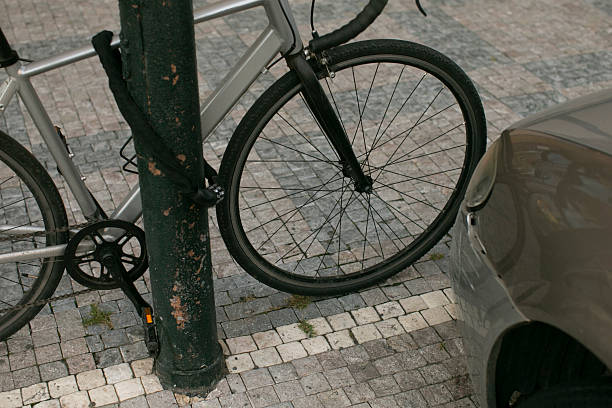 istock A bicycle is securely chained to a pole that is located next to a car 2235124556