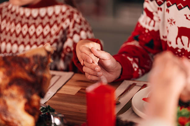 istock Family holding hands at christmas dinner table 2235128435