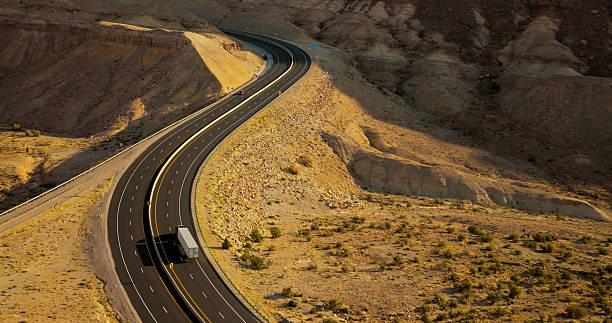 Aerial shot of winding road curving through Spotted Wolf Canyon, Emery County, Utah on a sunny day.