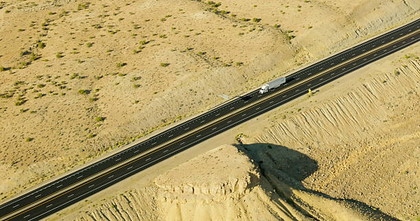 Aerial shot of semi-truck driving on highway through Spotted Wolf Canyon, Emery County, Utah on a sunny day.