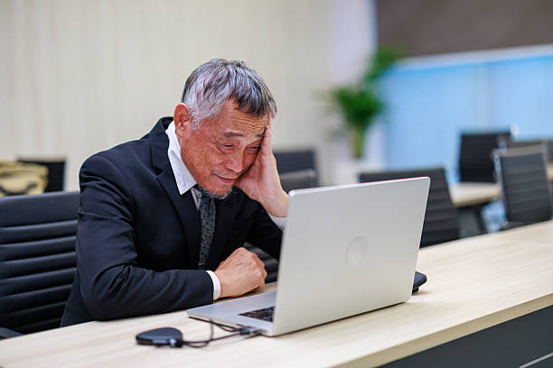 istock Stressful senior businessman working with laptop in modern office while facing corporate pressure and financial challenges highlighting workplace stress management and business strategy issues 2235130228