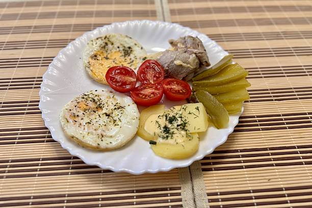 istock Round fried eggs with tomatoes on a white plate on a tablecloth 2235146319