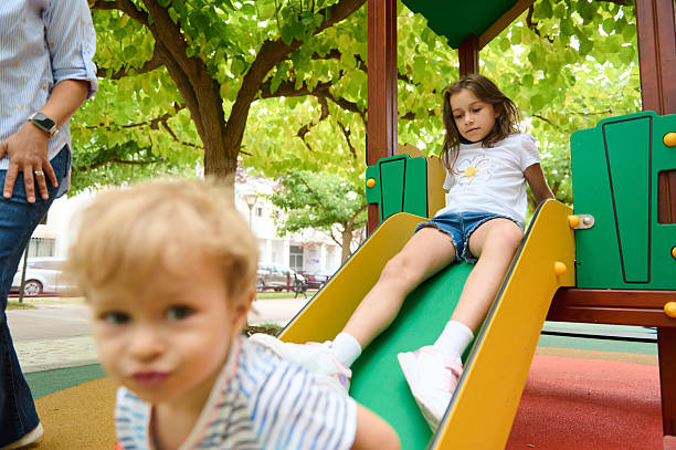 istock Children Playing Happily on a Slide at a Sunny Park Playground 2235151482