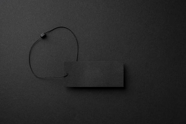 Minimalist black cardboard clothing tag with string on dark background
