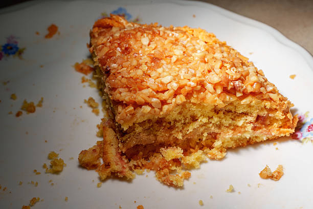 a delicious slice of nut cake on a white plate. the dessert is topped with golden, chopped nuts, creating a cozy and mouth-watering scene