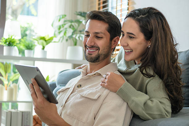 Couple using tablet together at home browsing streaming media and enjoying digital lifestyle connection.