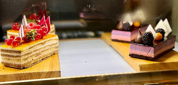 A portion of layered cream yellow cake with red raspberries, red currants, blackberries on a wooden stand